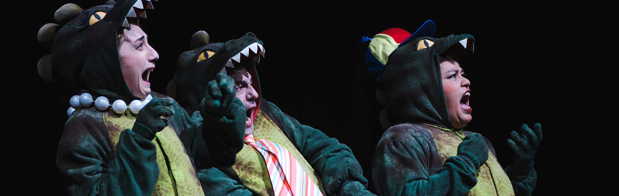 Three people with surprised looks dressed in dinosaur costumes.