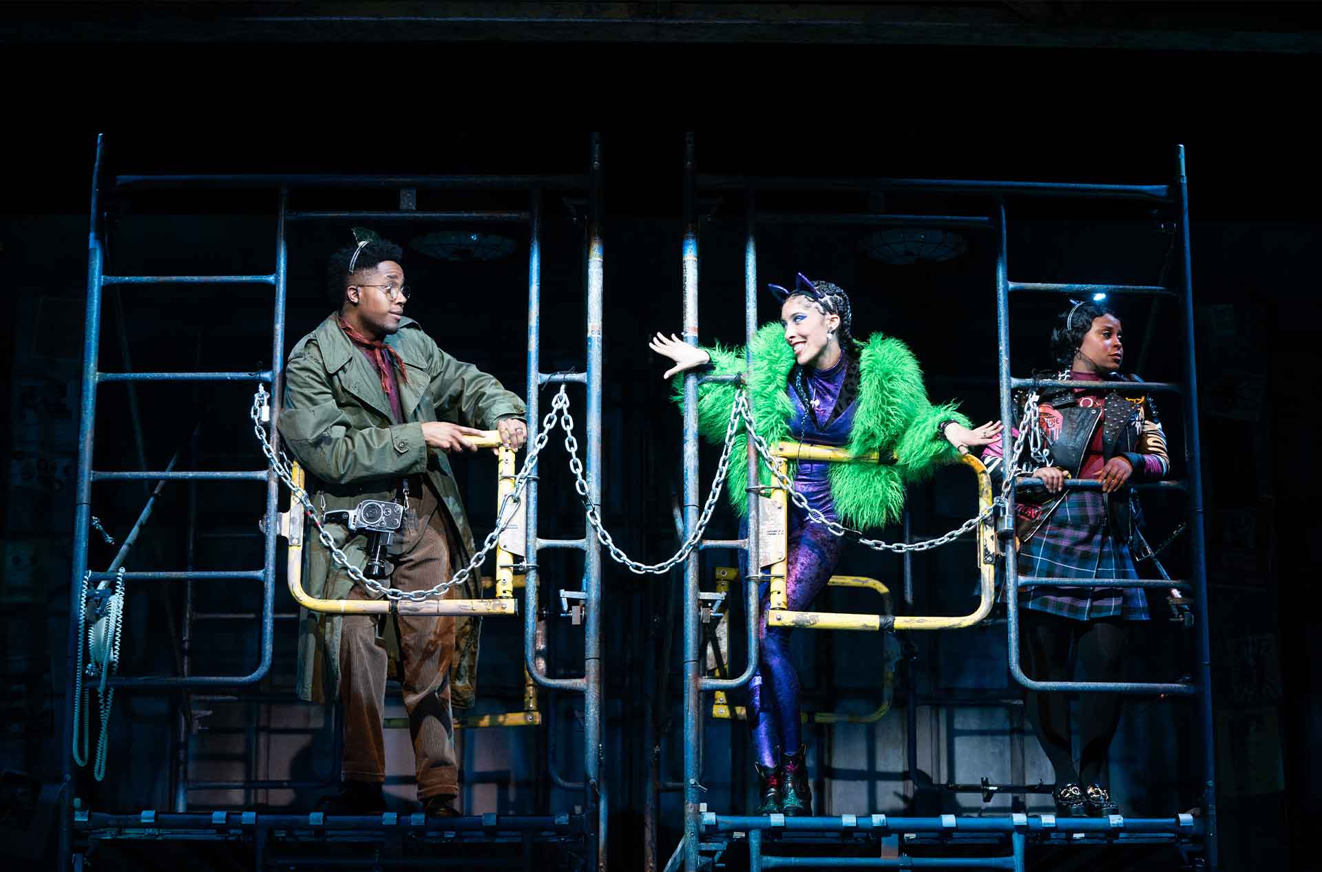 Three people leaning on metal ladder and railing while one appears to talk.