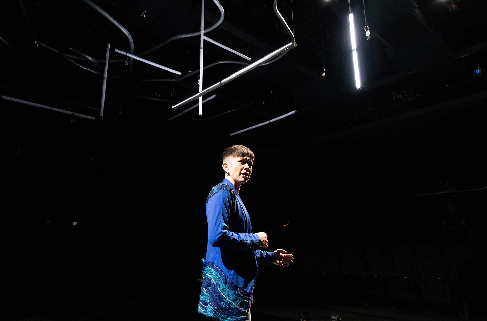 A person standing on the stage looking out toward the audience. 