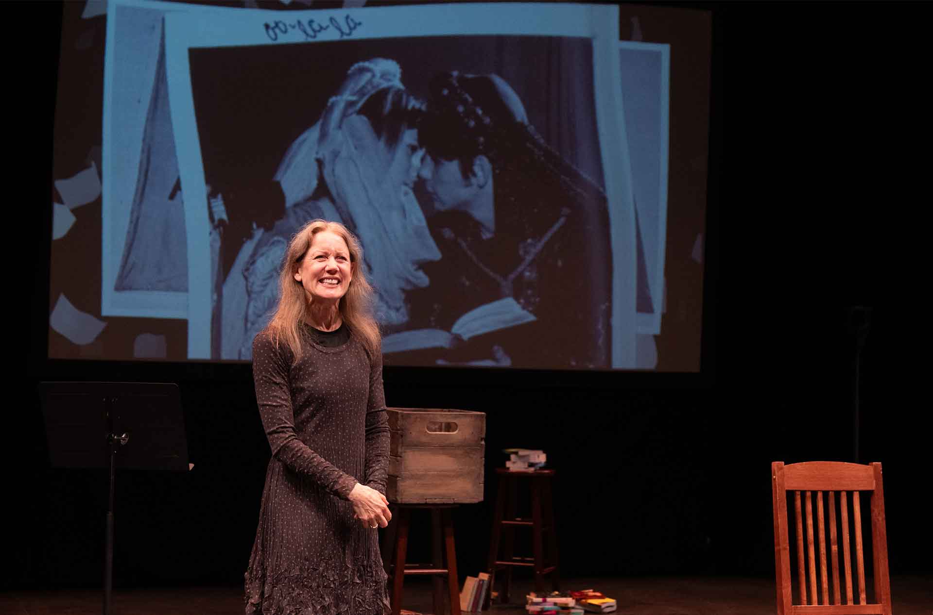 A woman standing in front of a projected photo smiling.