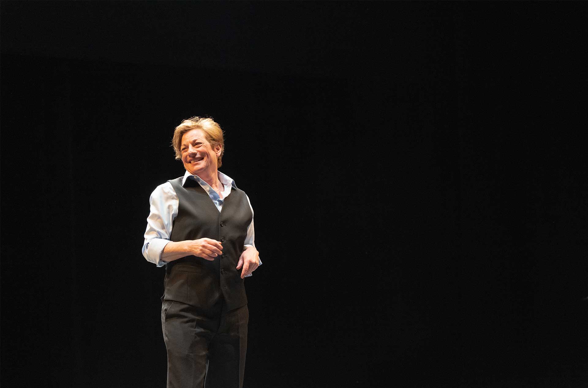 A person standing before a dark background smiling out.