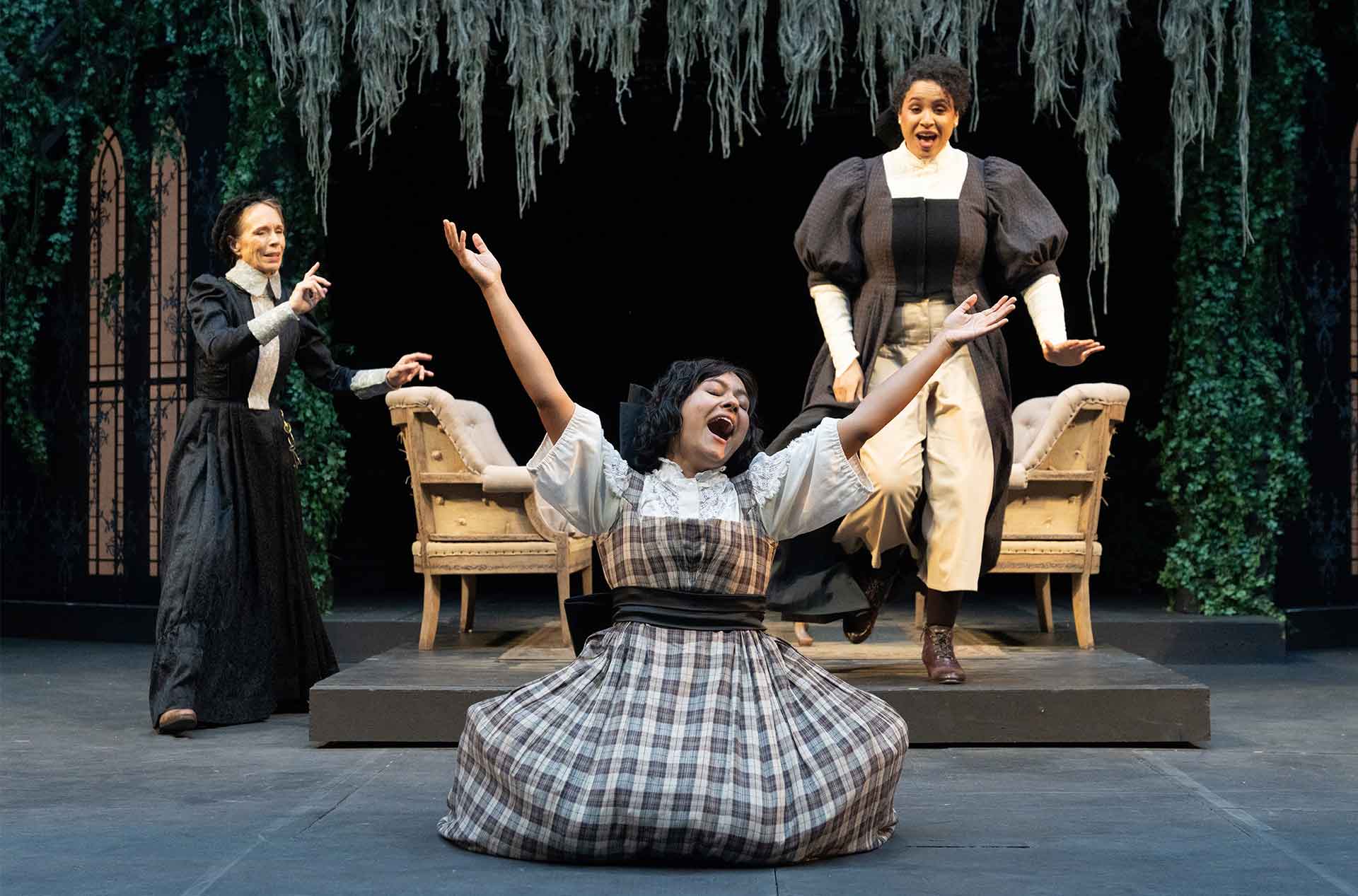 A person in the foreground, kneeling with their arms in the air while two others are standing in the background.