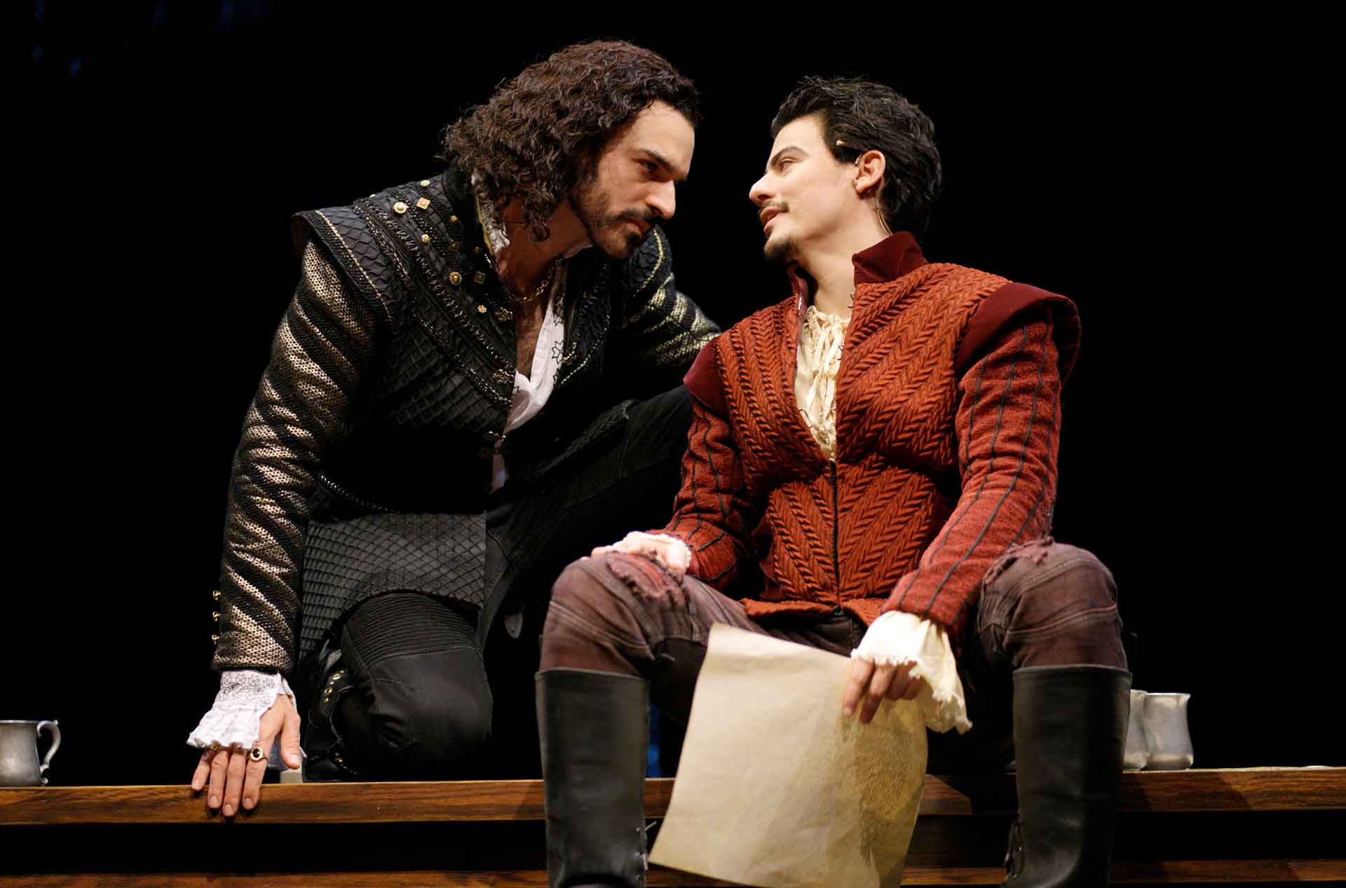 Two people sitting on a desk looking at each other.