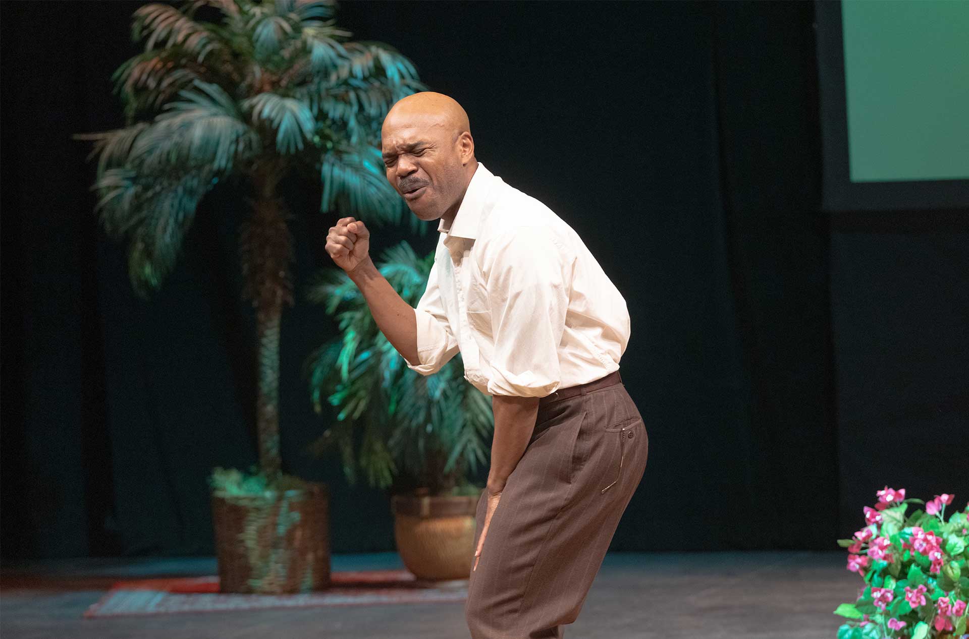 A person standing in a leaning position with his fist by his face.