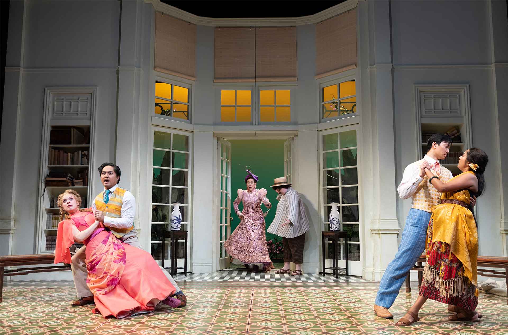 Two pairs of dancers move passionately in an elegant room, while a third pair enters dramatically from the background.