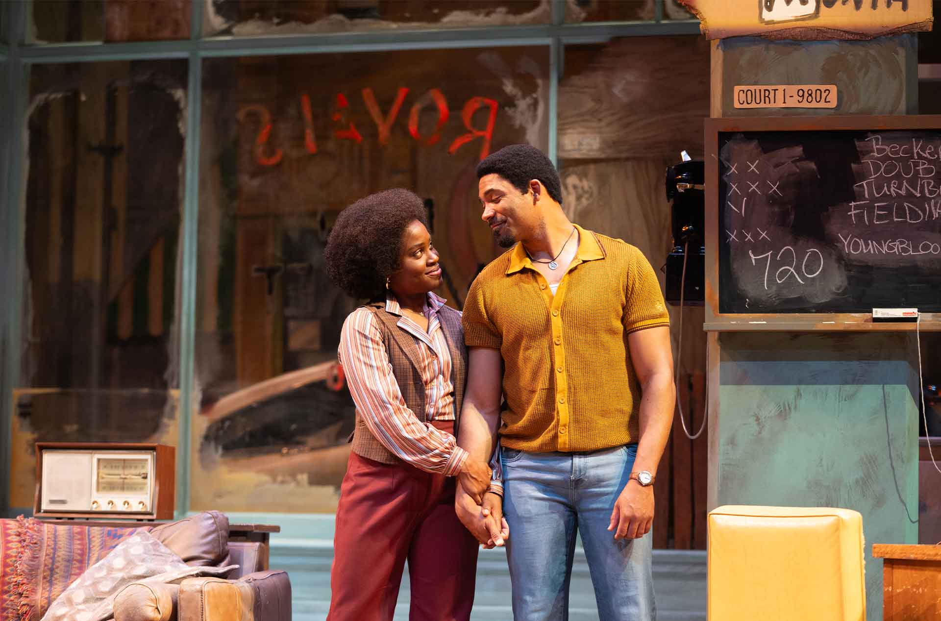 A warm moment between two people standing close together, holding hands and gazing at each other with smiles.