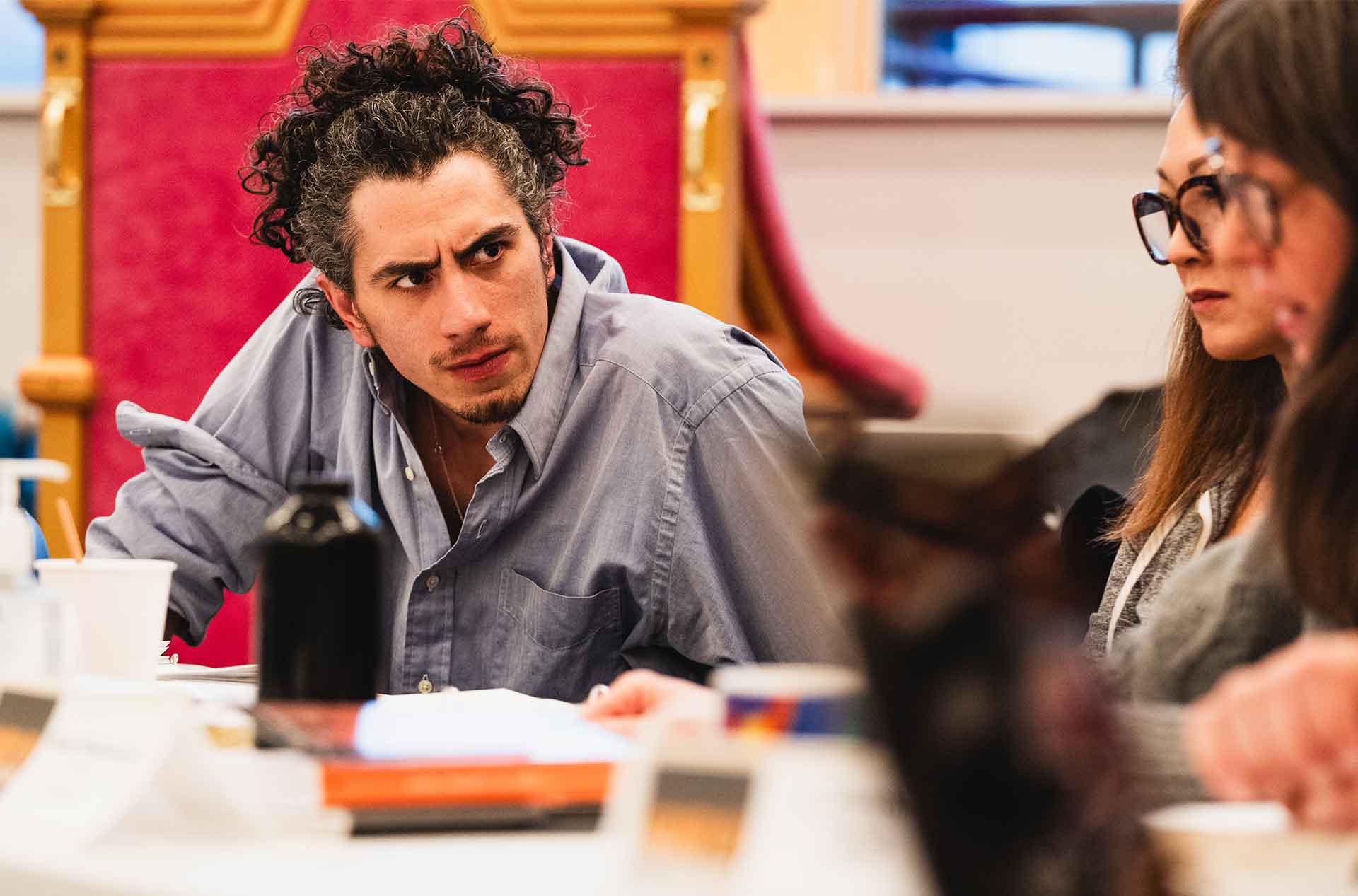 Performer leaning forward while listening closely during a rehearsal discussion.