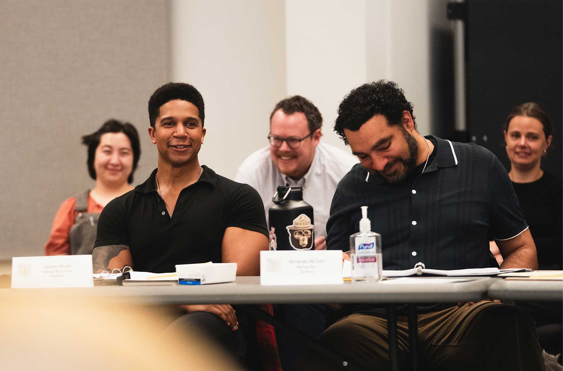 Group of participants sharing a laugh at the table during a read-through session.