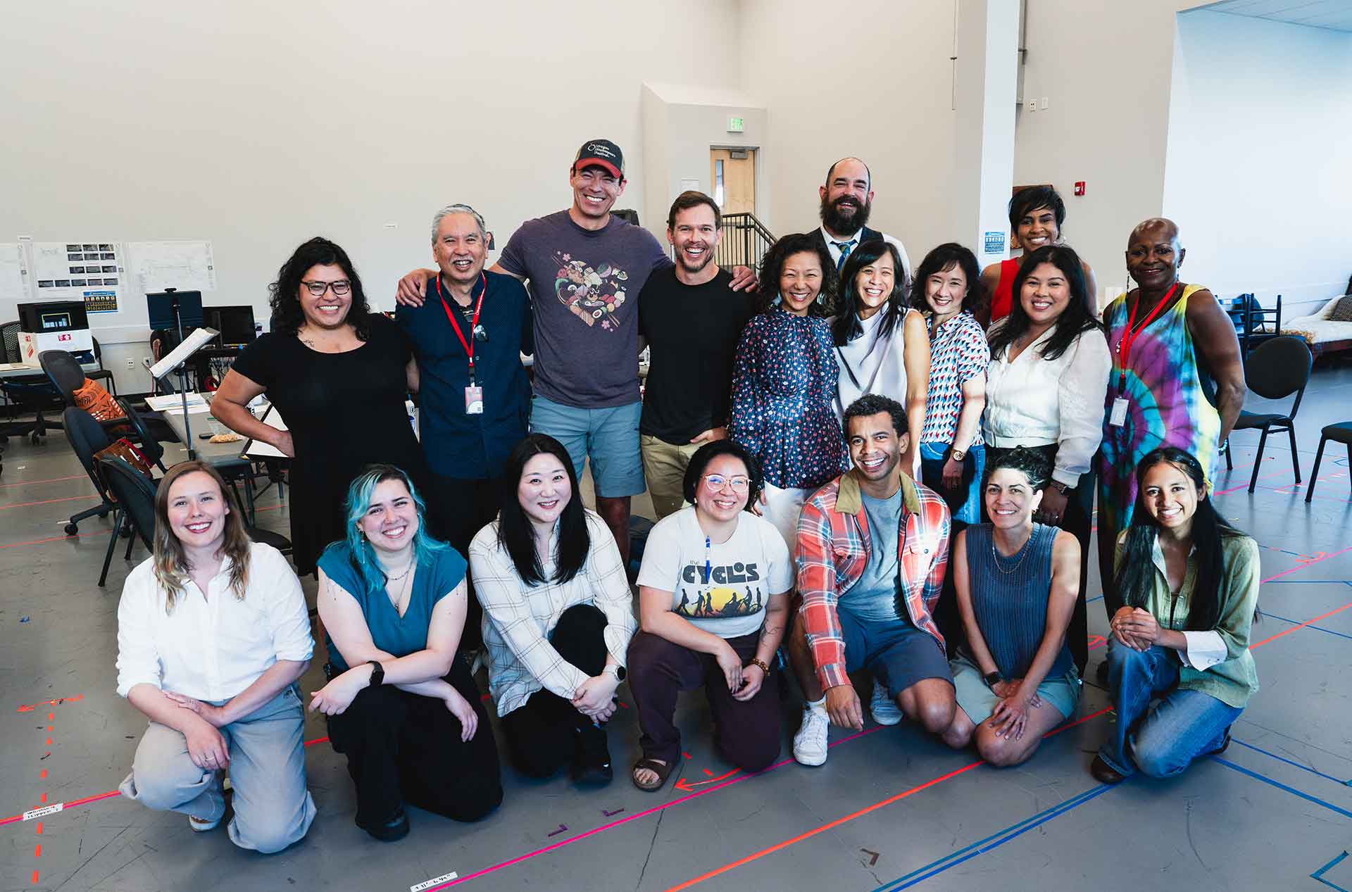 Cast and crew posing together in a rehearsal room