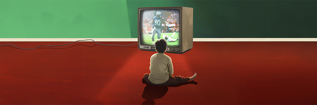 A boy sitting in front of a tv with a football game on.