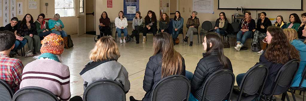 Group of people sitting in a large circle having a discussion.