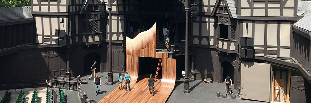 A view of the Allen Elizabethan stage with crews setting up a set.