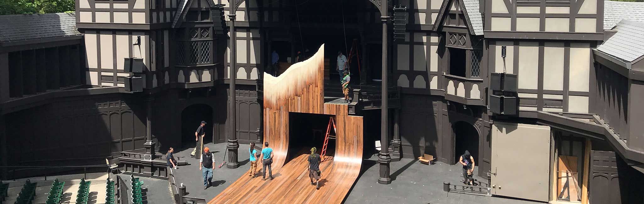 A view of the Allen Elizabethan stage with crews setting up a set.