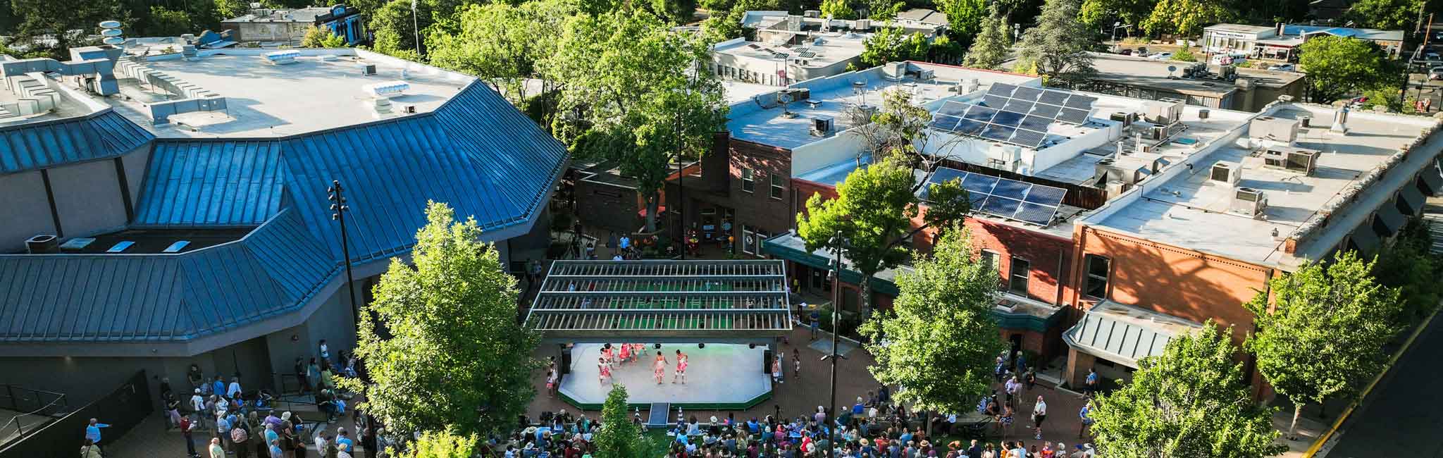 OSF campus aerial view with outdoor performance space, surrounding theater buildings, and tree-lined walkways.